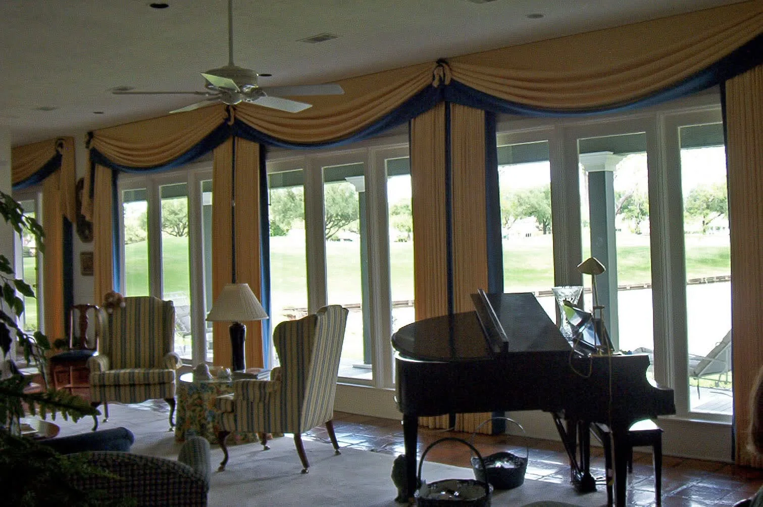 Living room with layered custom drapery installed across tall windows